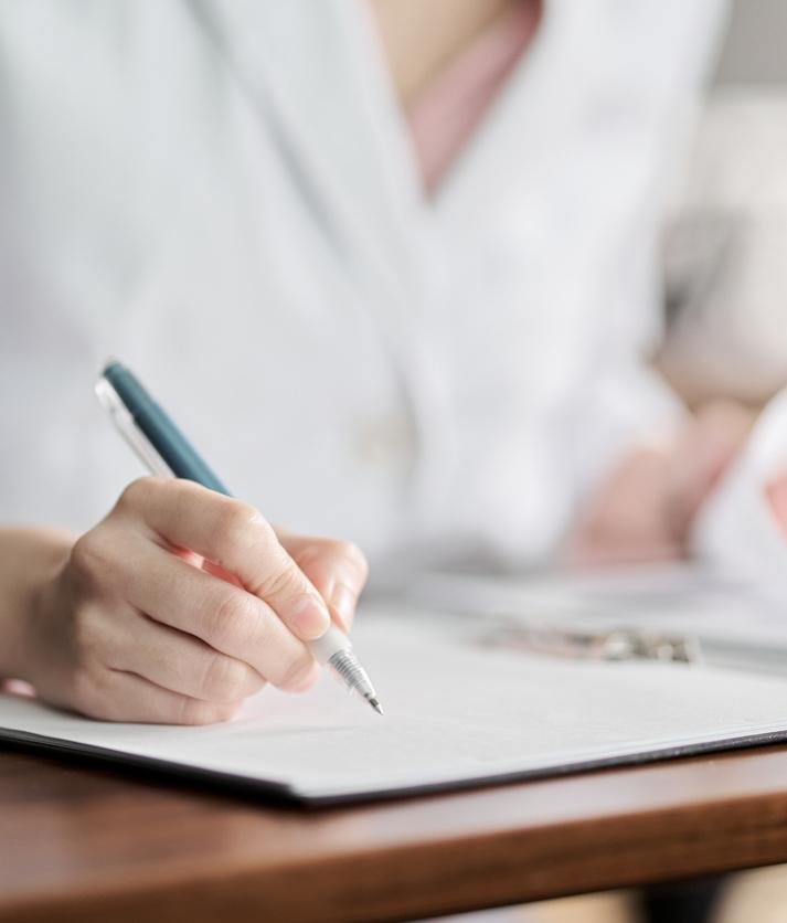 Médecin rédigeant des notes lors d'une consultation de suivi après un avortement.